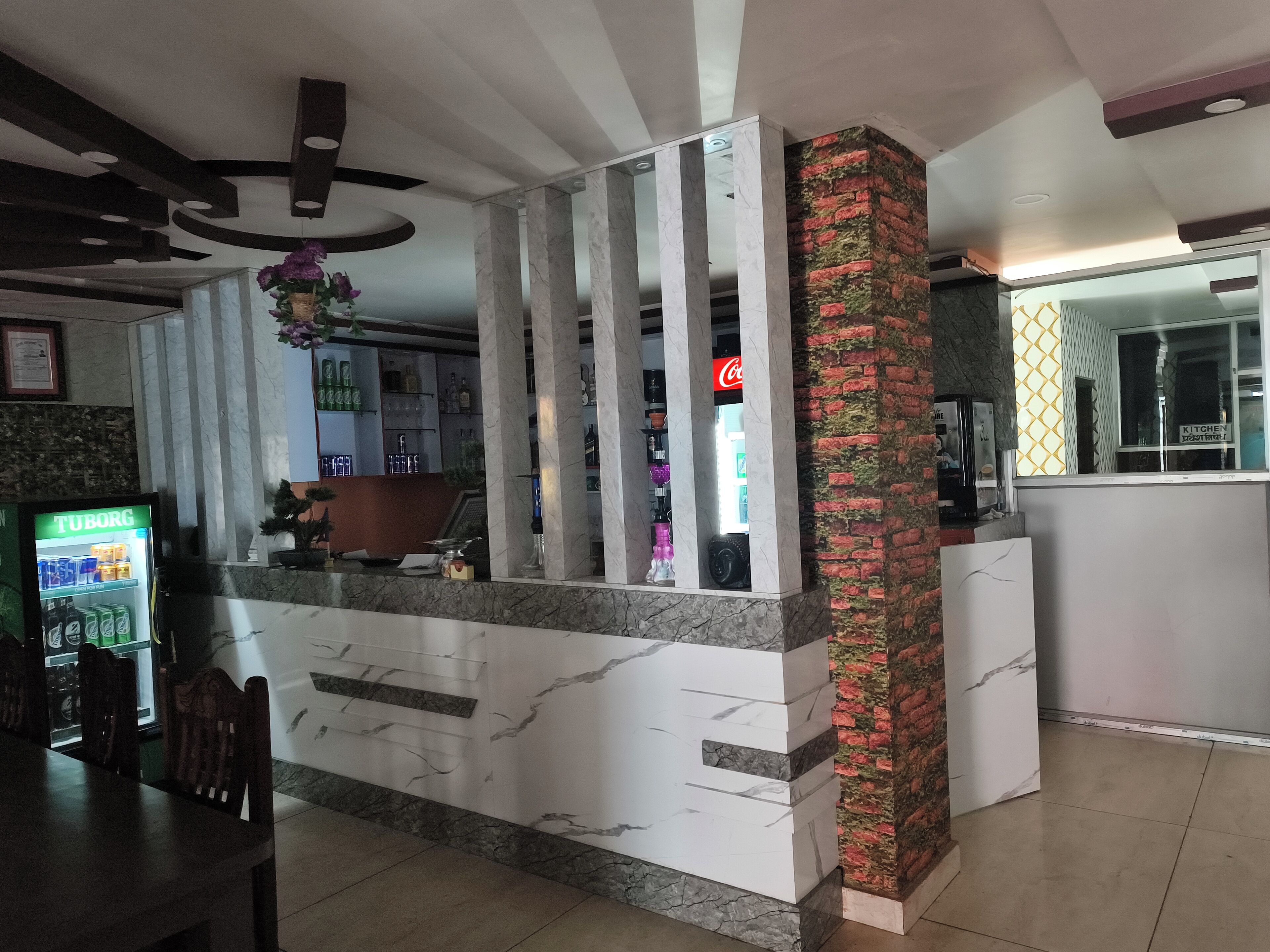 A reception area with a marble counter, a Coca-Cola refrigerator, and a vending machine.