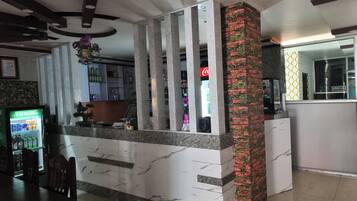A reception area with a marble counter, a Coca-Cola refrigerator, and a vending machine.