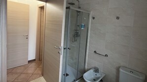 Une salle de bain avec une douche à parois de verre, un bidet et des toilettes.