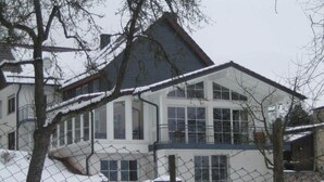 Et stort, tosset hus med et sneklædt tag og en indhegnet have.