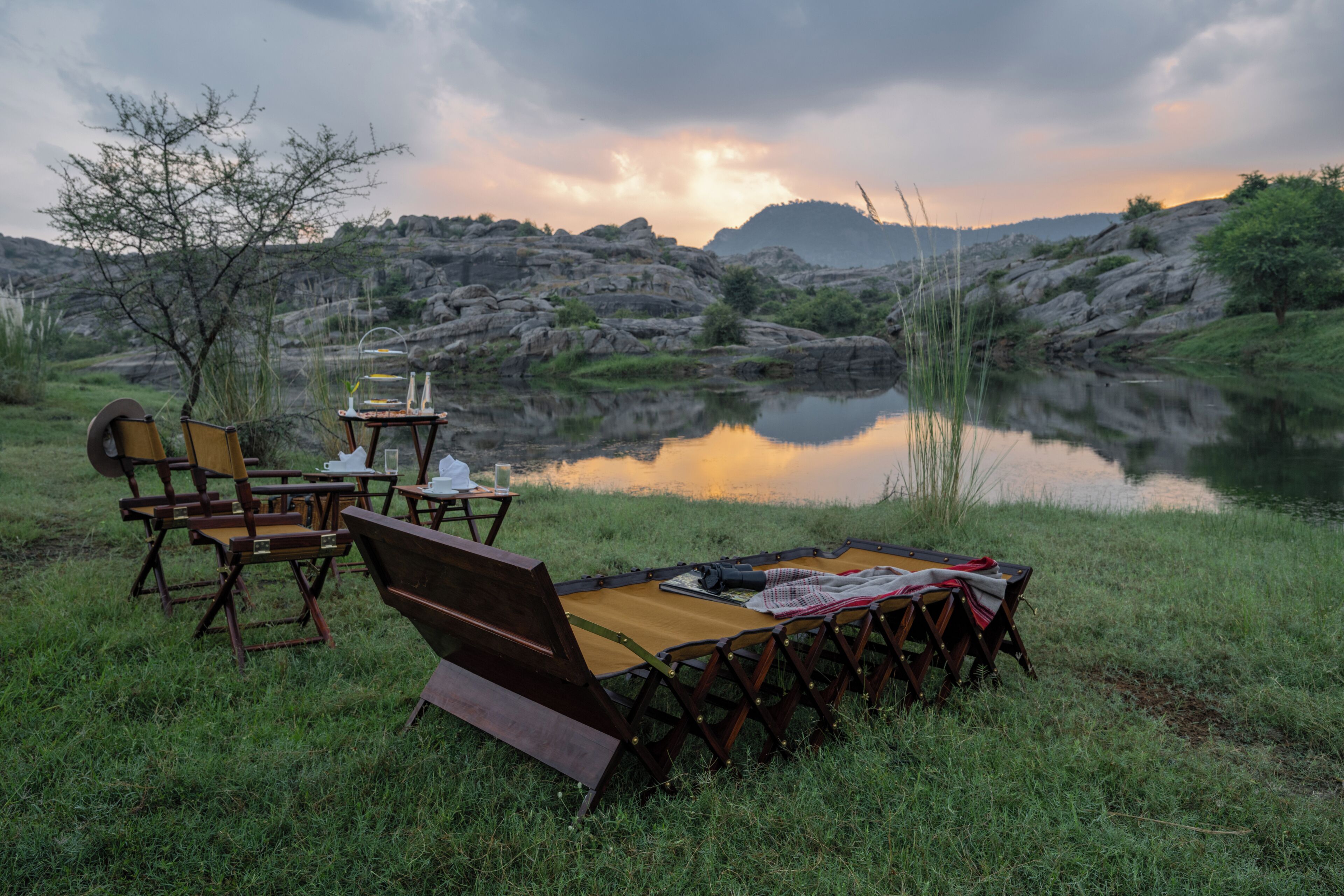 Montaje para picnic junto al lago, con sillas, una mesa y una manta.