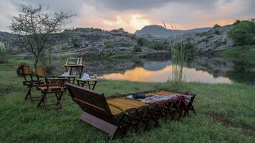 Montaje para picnic junto al lago, con sillas, una mesa y una manta.
