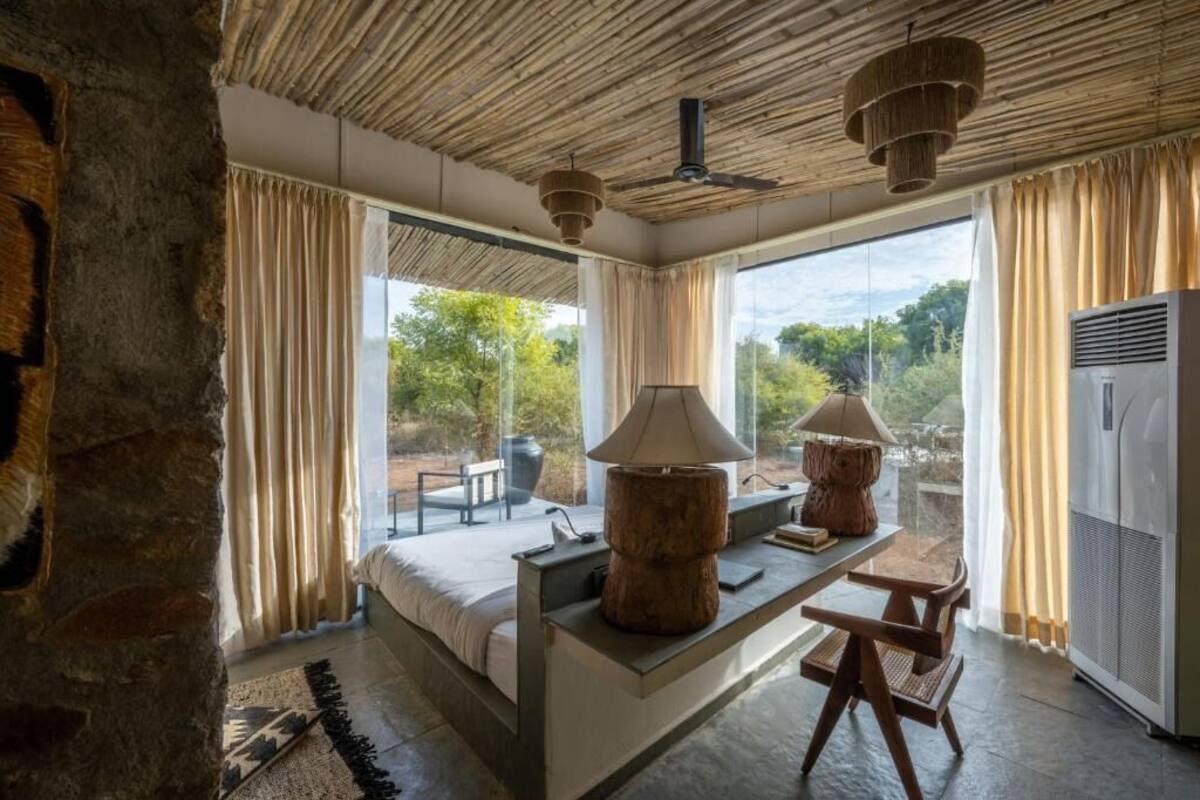 Ein modernes Schlafzimmer mit einem großen Bett, einem Holztisch und Blick ins Freie.