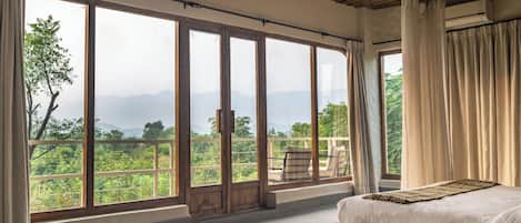 Un dormitorio con un ventanal grande, una cama y vistas al verdor.