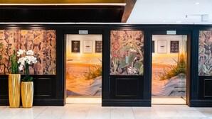 A reception area with a wooden wall and a large potted plant. - Ocean Suite von OstseeAhoi (Timmendorfer Strand)