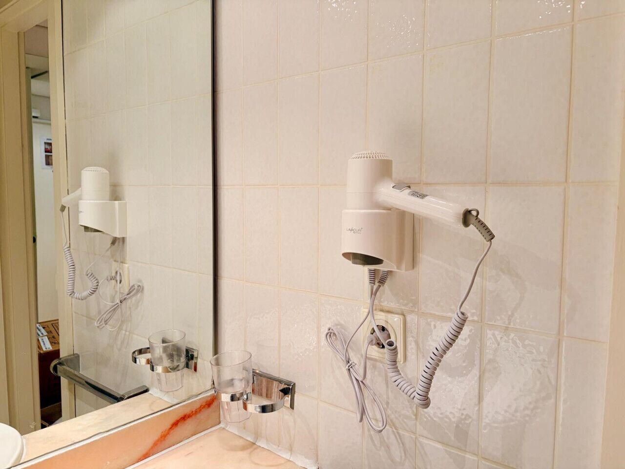 A bathroom with a mirror, a hairdryer, and a towel rack.