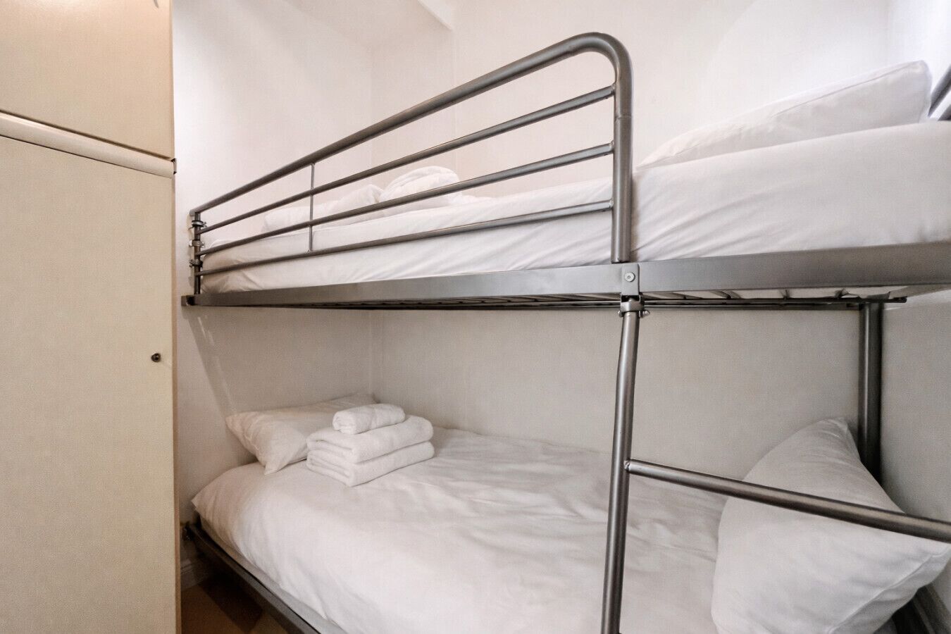A bunk bed with white bedding and a metal frame.