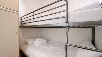 A bunk bed with white bedding and a metal frame.