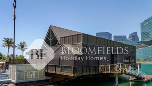 A modern holiday home with a unique floating design, featuring a large deck and a view of the water. - Bloomfields 1Br Supremee Al Maryah  (Abu Dhabi)