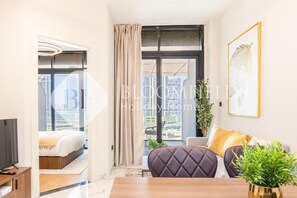 Een moderne hotelkamer met een bed, een televisie, een eettafel en een bank.
