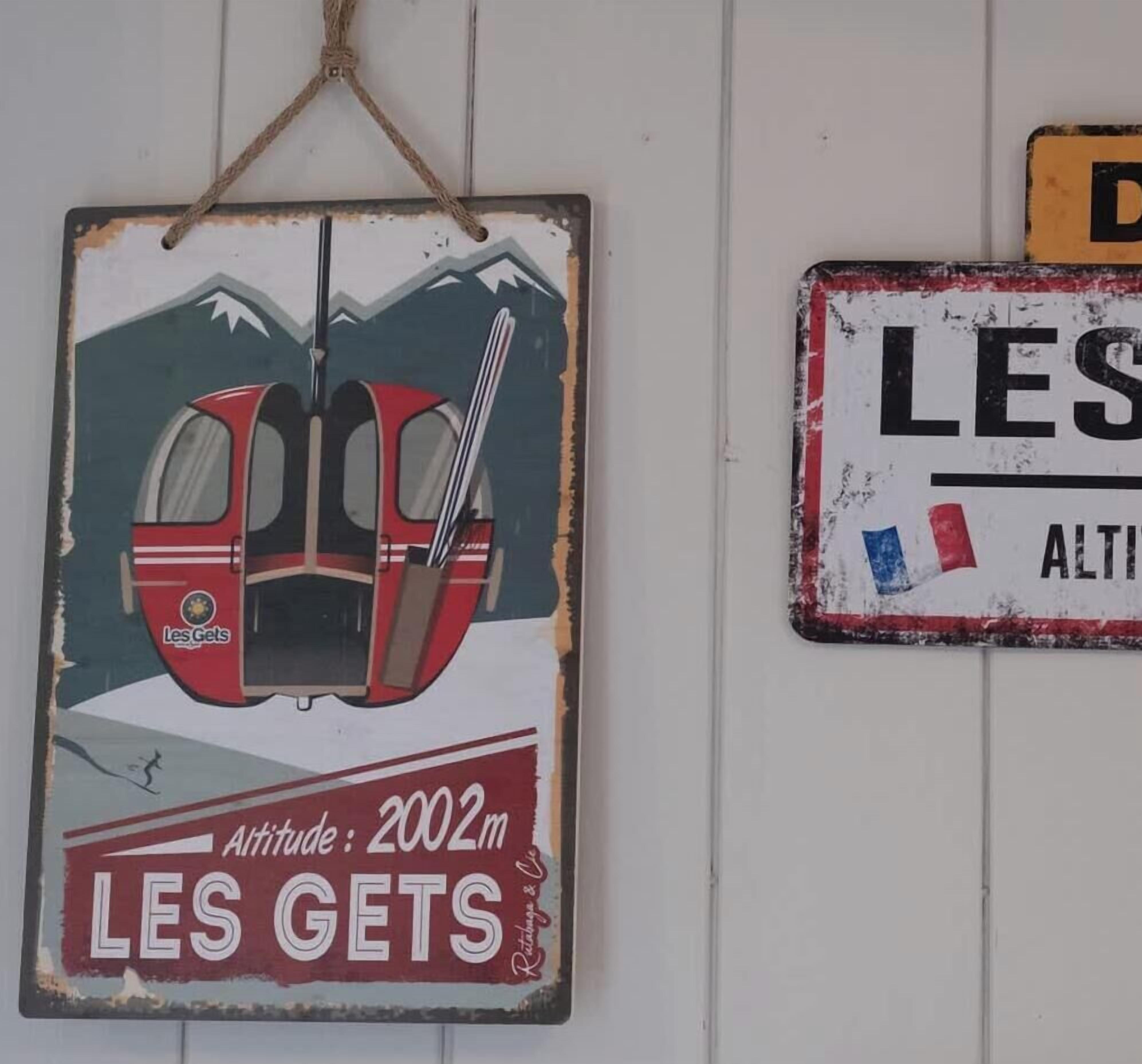 Two vintage-style signs with text and graphics, one depicting a train and the other with a partial word 'LES'.