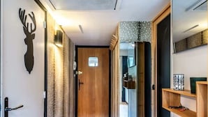 Un pasillo con una puerta de madera, un espejo y una estantería con un marco de fotos.