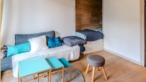 Una habitación acogedora con sofá, una mesita y un banco. El suelo es de madera y el techo tiene vigas de madera.
