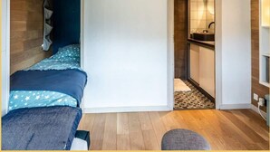 Un dormitorio con cama, una decoración de cabeza de venado montada en la pared, suelo de madera y un baño visible a través de una puerta abierta.