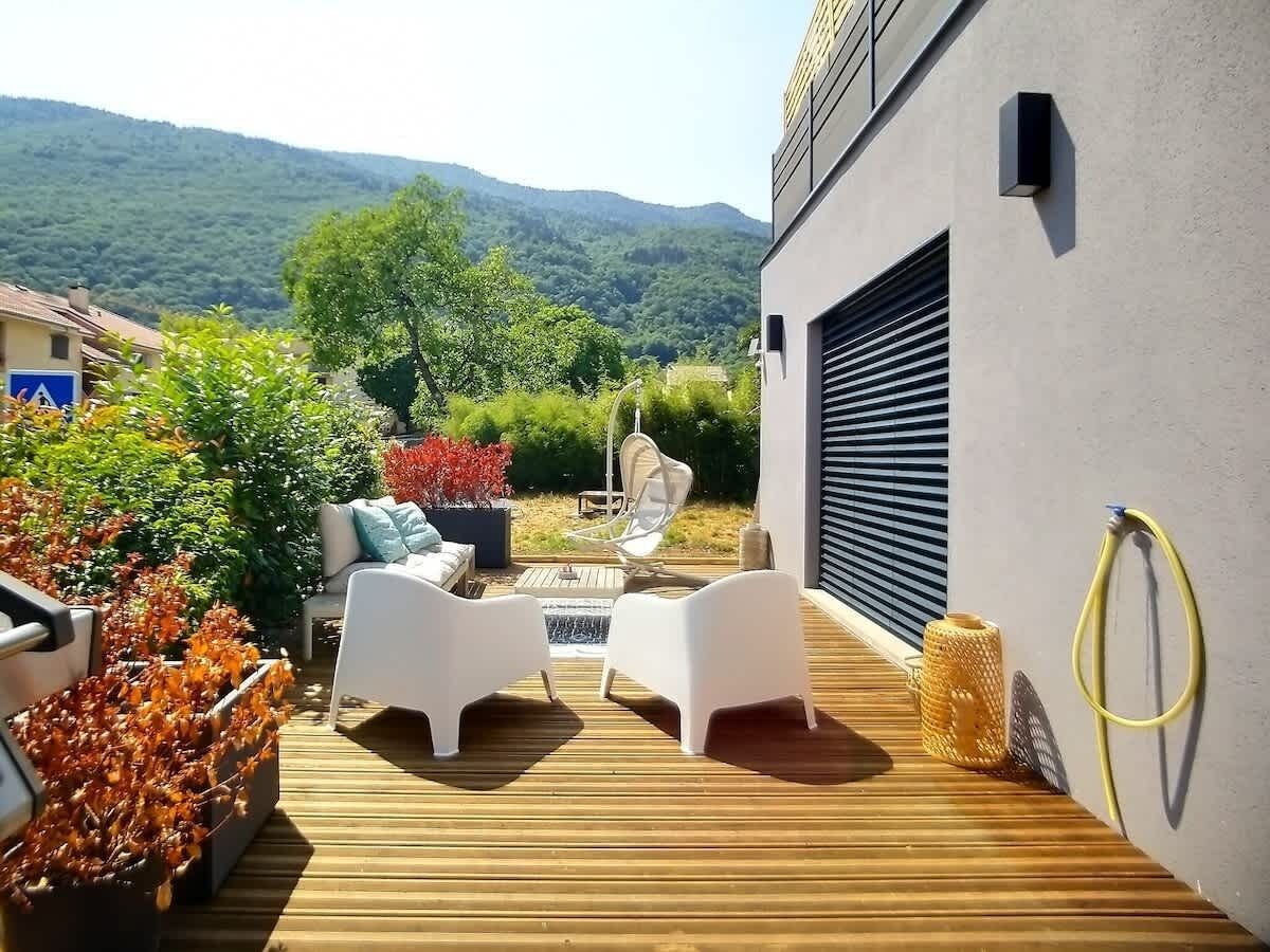 An outdoor deck with white furniture, a fire pit, and a view of a mountainous landscape.