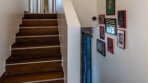 A wooden staircase leading to a room with a ceiling light fixture and a door. - Villa Amadieu · Détente, confort et sérénité, aux portes de Genève (Collonges)