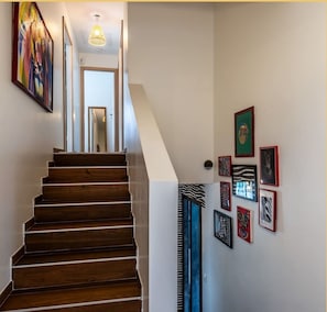 A wooden staircase leading to a room with a ceiling light fixture and a door.