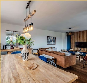 Un salon moderne avec une table à manger en bois, un canapé et un téléviseur fixé à un mur en bois.