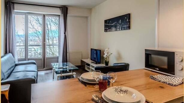 A modern living room with a sofa, a glass dining table, and a TV. There are three pendant lights above the table. - Chez Dams I T2 I Annecy (Annecy)
