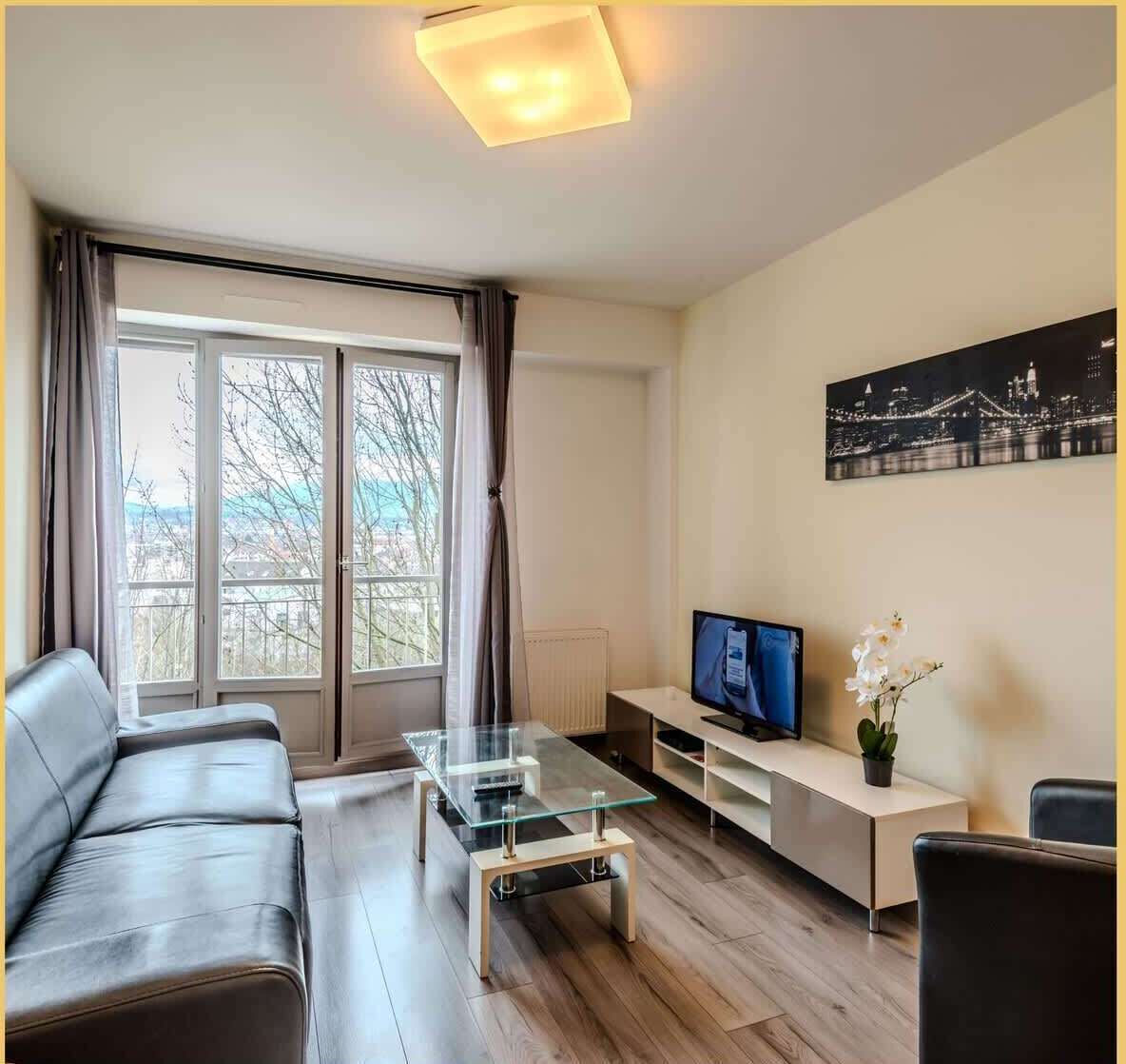 Un salon moderne avec une table basse en verre, un canapé en cuir et un téléviseur posé sur un meuble.