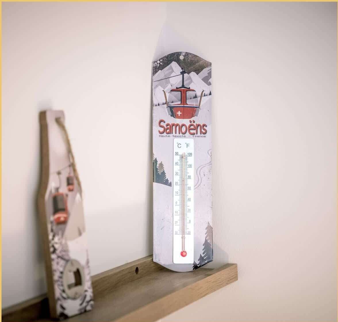 Een thermometer aan de muur, met een berg- en skipiste-illustratie, die een koud klimaat aangeeft.