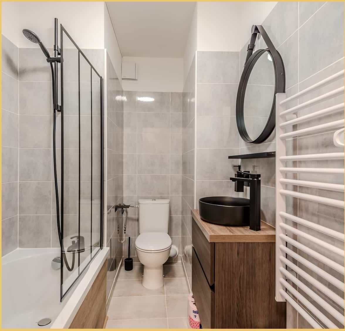A compact bathroom with a glass-enclosed shower, a toilet, and a sink with a mirror above it.
