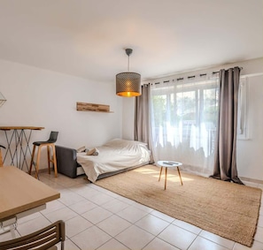 A modern bedroom with a bed, a dining table, and a hanging light fixture.