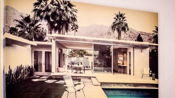 A modern house with a swimming pool, large windows, and palm trees.