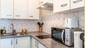 A compact kitchen with white cabinets, a microwave, a toaster, and a sink.
