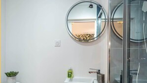 A modern bathroom with a toilet, a sink with a mirror above it, and a glass shower enclosure. - Chez Carole I Studio I Annemasse (Annemasse)