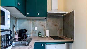 A compact kitchen with teal cabinets, a white refrigerator, a microwave, and a coffee maker. - Chez Carole I Studio I Annemasse (Annemasse)