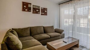 A living room with a sectional sofa, a wooden coffee table, and three framed pictures on the wall. - Le Manoir de Jérémy I T2 I Thonon (Thonon-les-Bains)