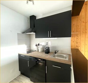 Een moderne keuken met zwarte kasten, een roestvrijstalen spoelbak en een vaatwasser.