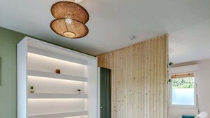 Une chambre moderne comprenant un lit, des étagères intégrées, une cloison en bois, une fenêtre et une chaise.