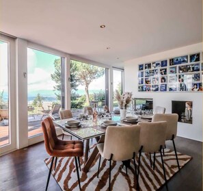 A dining area with a glass table, chairs, and a view of the outdoors.