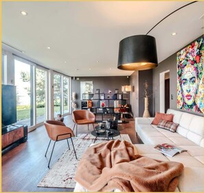 A modern living room with a sofa, chairs, a coffee table, and a bookshelf.