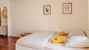 Ein Schlafzimmer mit einem Bett, zwei gerahmten Bildern an der Wand und einem Nachttisch.