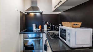 Een kleine keuken met een kookplaat, oven, magnetron en een klein aanrecht.