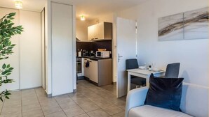 Een modern appartement met een kitchenette, een eethoek en een woonkamer met een bank en een salontafel.