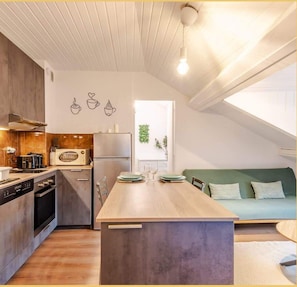 Une cuisine moderne avec un îlot central en bois, un coin repas et un canapé vert.
