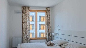 Ein Hotelzimmer mit einem großen Bett, einem Heizkörper und einem Fenster mit gemusterten Vorhängen.