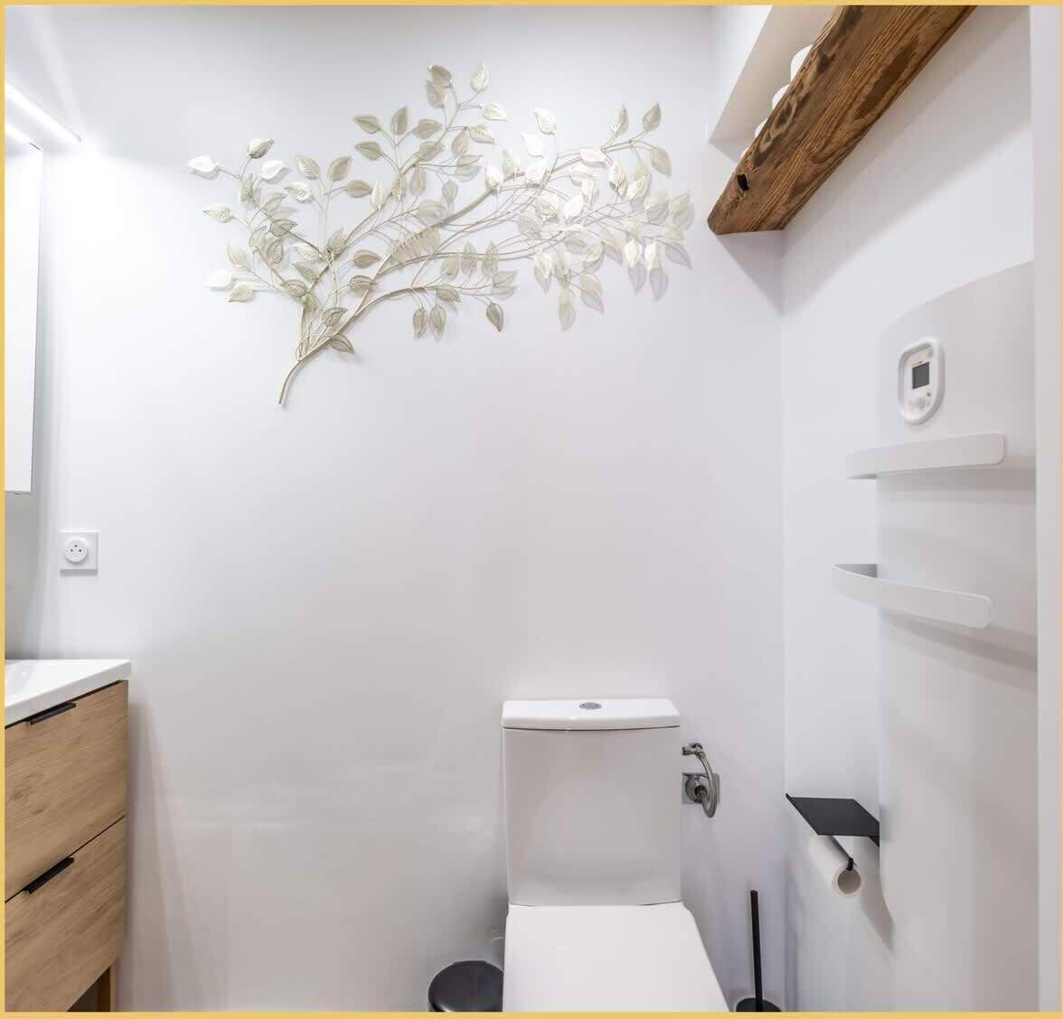 A bathroom with a white toilet, a wooden cabinet, and a wall-mounted shelf.