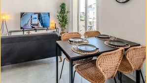 Ett modernt matområde med flätade stolar, ett mörkt bord och en väggklocka.