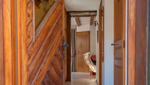 Un pasillo de madera con un tapete que lleva a una habitación con una cama y un objeto rojo en el suelo.
