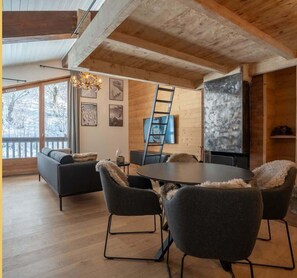A modern living room with a wooden ceiling, a round dining table, and a sofa. - The Nest - Votre cocon alpin à Megève (Megève)