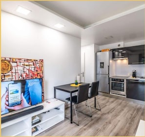 A modern kitchen with a built-in oven, a refrigerator, and a microwave. There is a dining table with chairs and a small plant on the table. - Chez Pat' I T2 I Saint-Julien (Saint-Julien-en-Genevois)