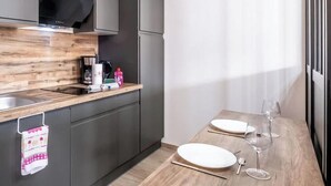 Une cuisine moderne dotée d’un plan de travail en bois, d’une cuisinière encastrée et d’un coin repas avec une table en bois mise pour deux personnes.