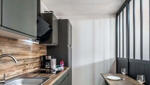 Une cuisine compacte dotée d’un plan de travail en bois, d’un évier en acier inoxydable et d’un coin repas avec une table et des chaises.