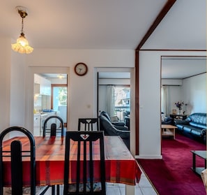 Un espace repas avec une nappe rouge, des chaises noires et un luminaire suspendu.