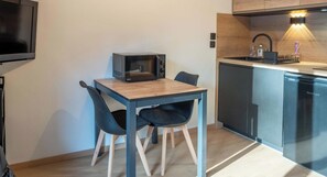 Une cuisine compacte équipée d’un four à micro-ondes, d’un évier et d’un lave-vaisselle. On y trouve une petite table avec deux chaises.
